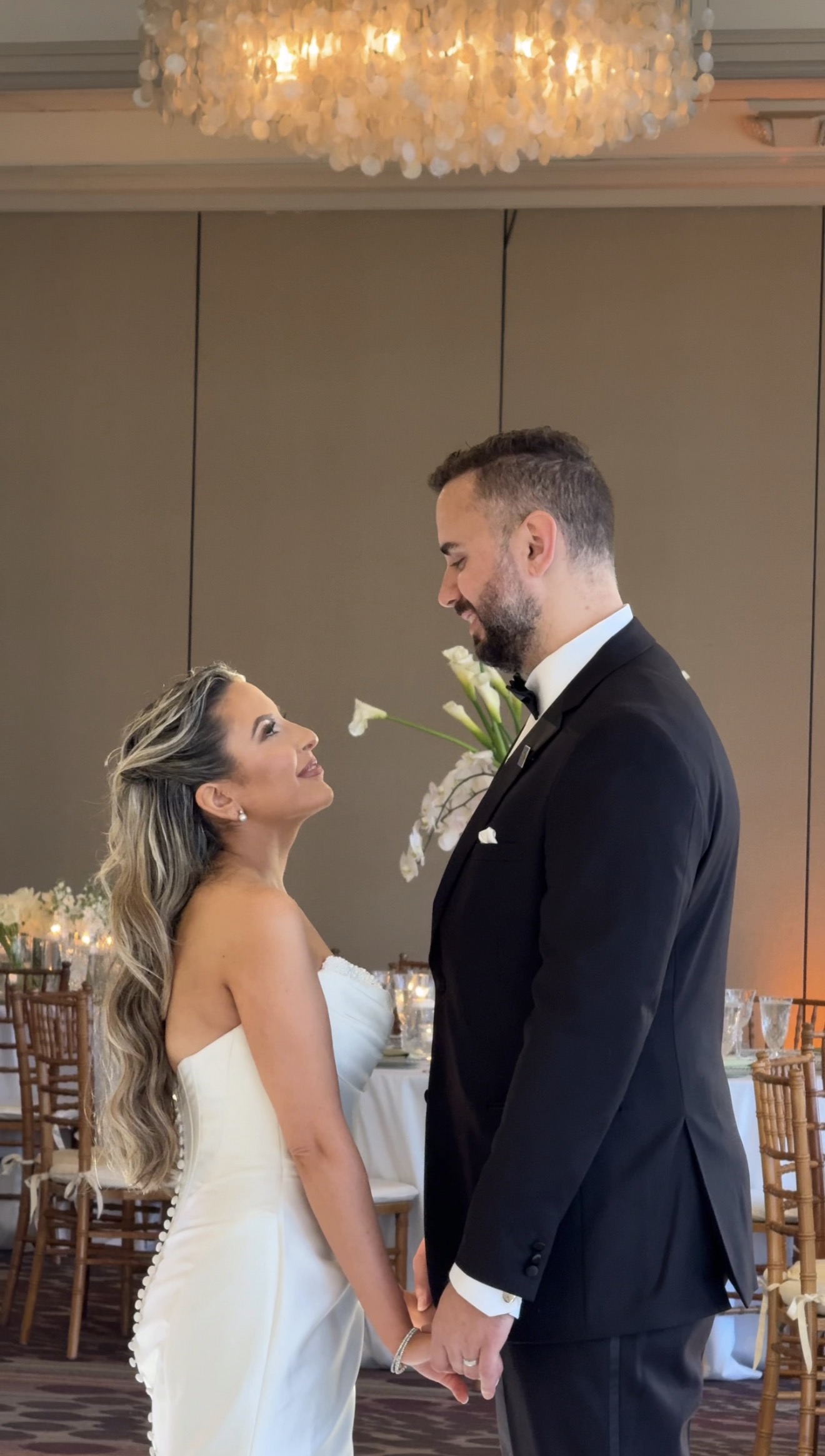 Bride and groom feeding cake under warm reception light