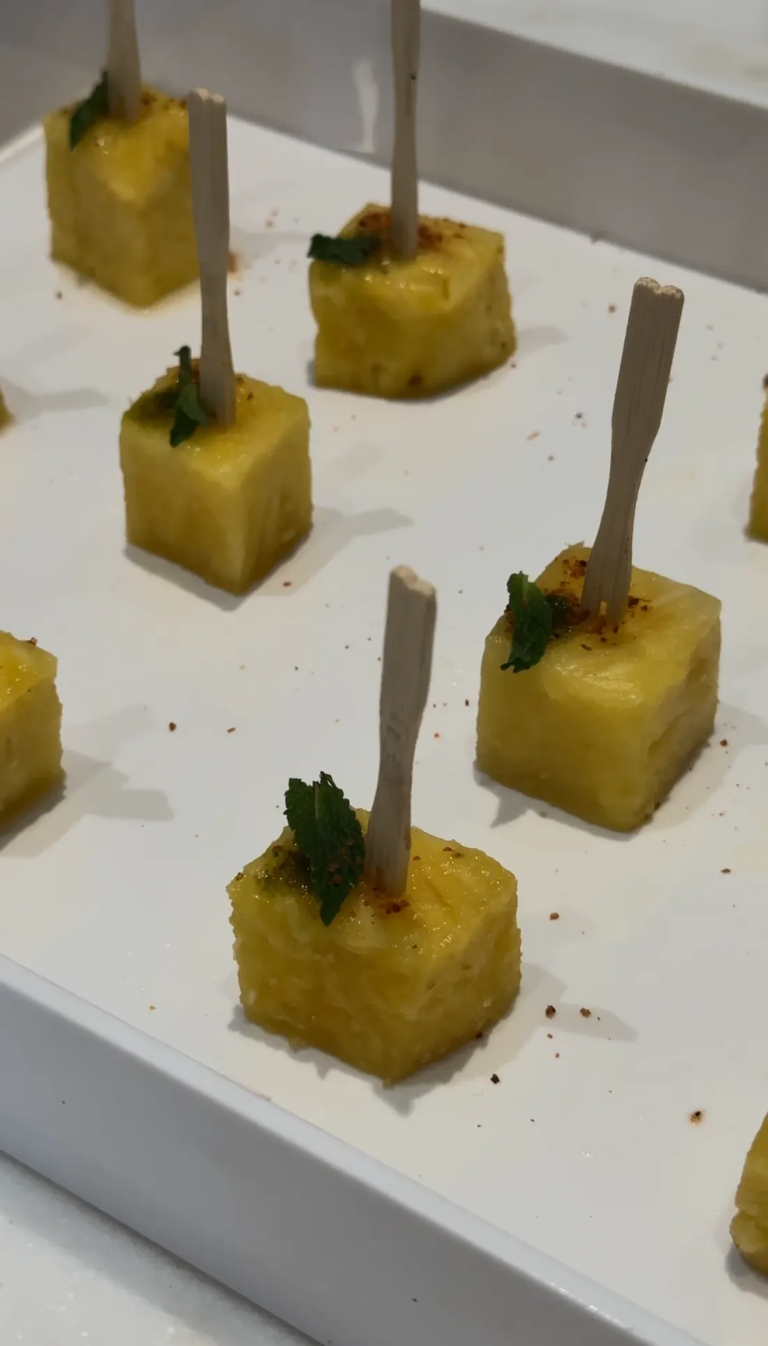Spiced pineapple bites with mint served on a white tray