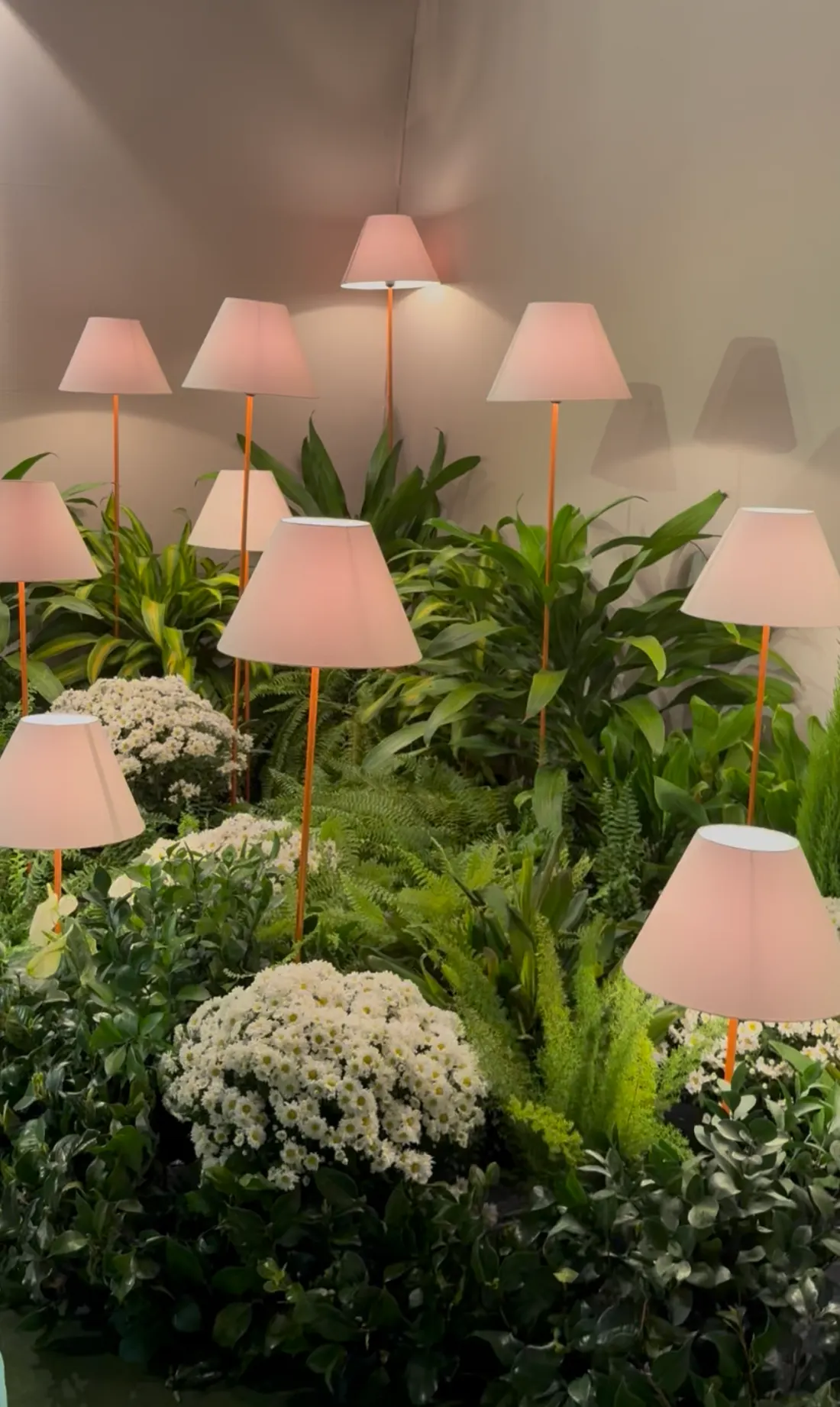 Blush lampshades rising from a lush garden installation