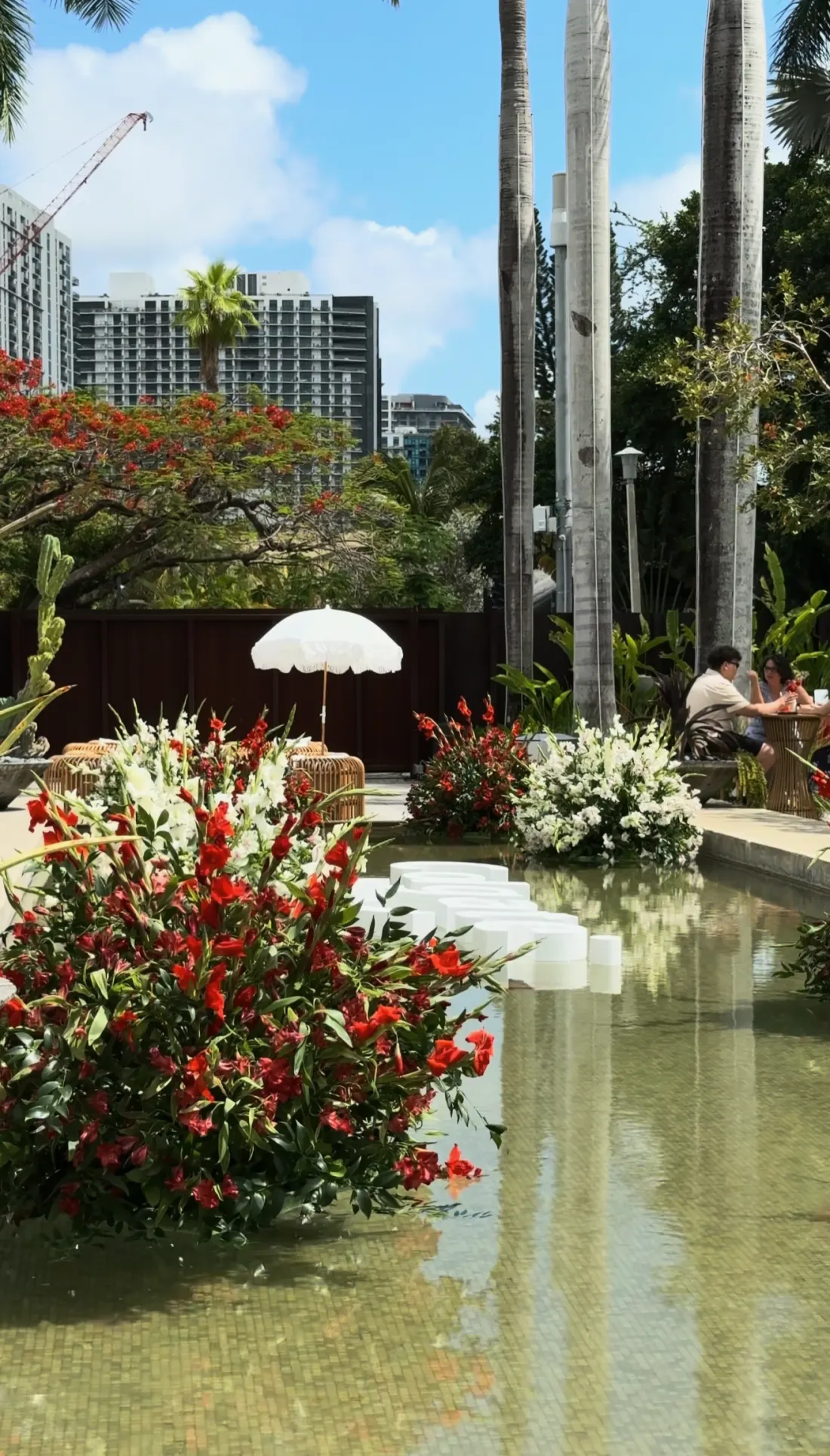 Red and white floral arrangements along a reflecting pool