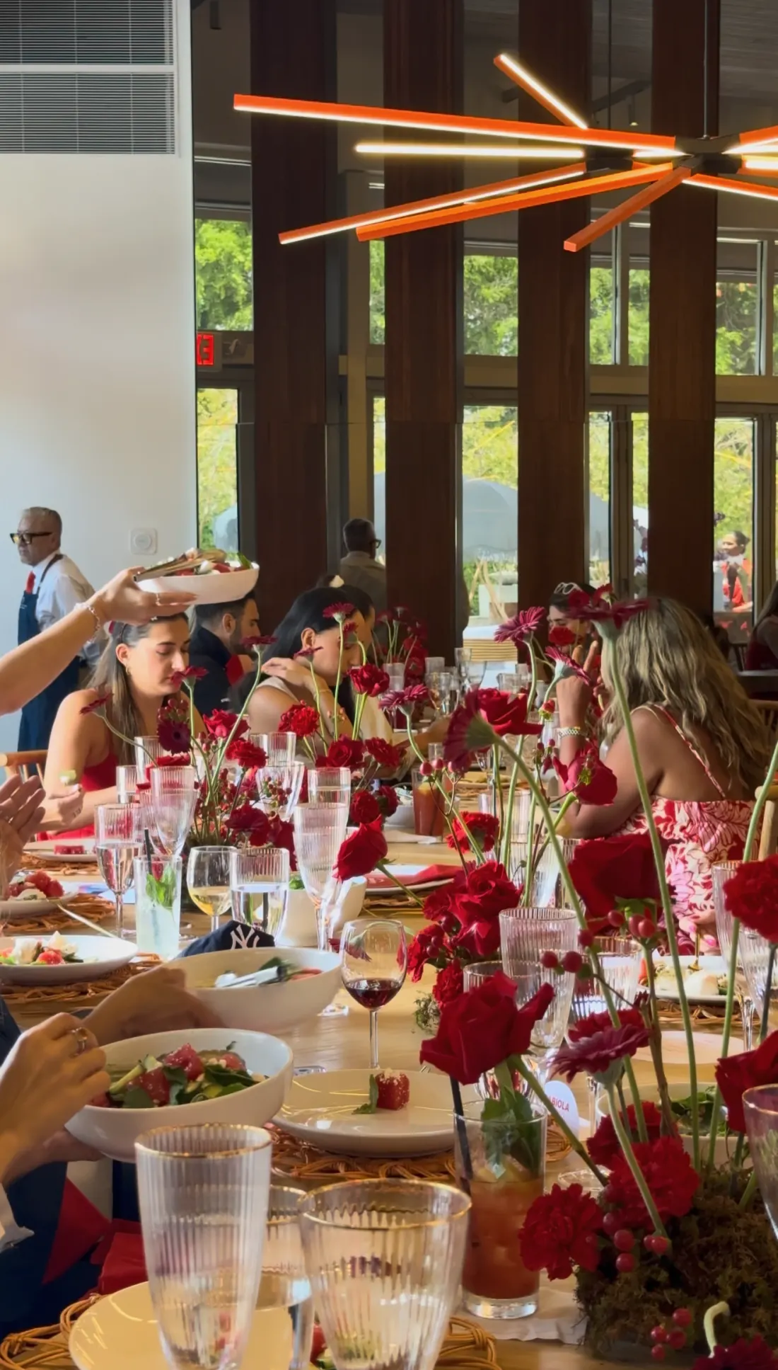 Guests at a long luncheon table styled with red roses
